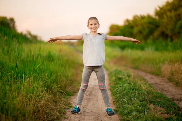 Маленькая девочка делает упражнения на открытом воздухе в surise — стоковое фото