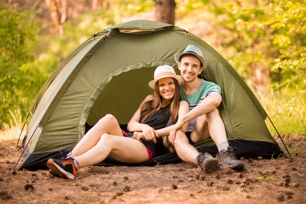 Romantic couple camping outdoors and sitting in tent. Happy Man and woman on romantic camping vacation.