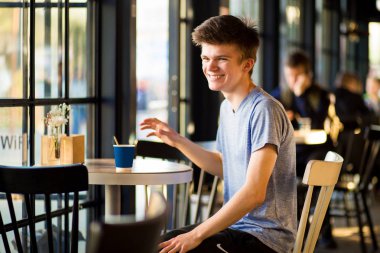 Gülümseyen Adam sıcak kahve bir fincan içme, kalabalık açık kafe.