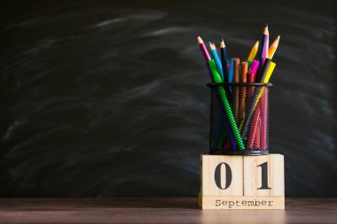 Gözlük ler masanın üzerinde kalemlerle, tahtanın arka planında tebeşirle duruyor. Öğretmenler günü kavramı. Kopyalama alanı.