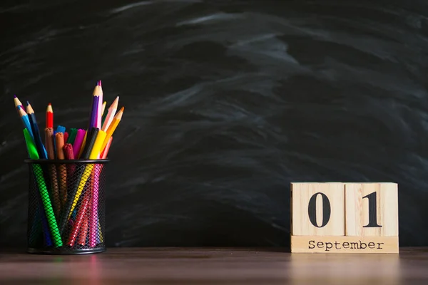 Bril stand met potloden op tafel, op achtergrond van Blackboard met krijt. Concept van leraren dag. Ruimte kopiëren. — Stockfoto