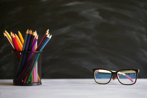 Professeur de lunettes et debout avec des crayons sur la table, sur le fond du tableau noir avec de la craie. Concept de journée des professeurs. Espace de copie . — Photo