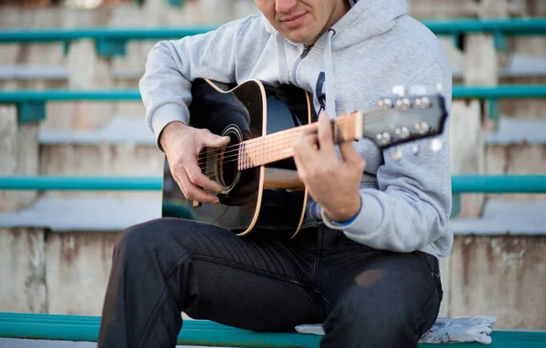 Joven sentado en los escalones tocando la guitarra y cantando, concepto musical — Foto de Stock