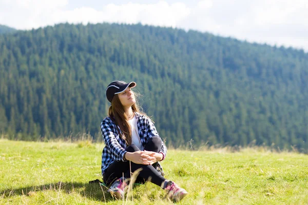 Mujer joven sentada en la cima de la montaña contemplando pacíficamente las nubes bajas de la mañana y el tranquilo amanecer — Foto de Stock