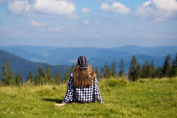 Udany Kobieta w czapkę na szczycie wzgórza cieszyć widok na szczyt górski — Zdjęcie stockowe