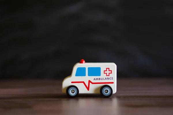 Ambulance service concept. Ambulance vehicle toy on black background with space for text