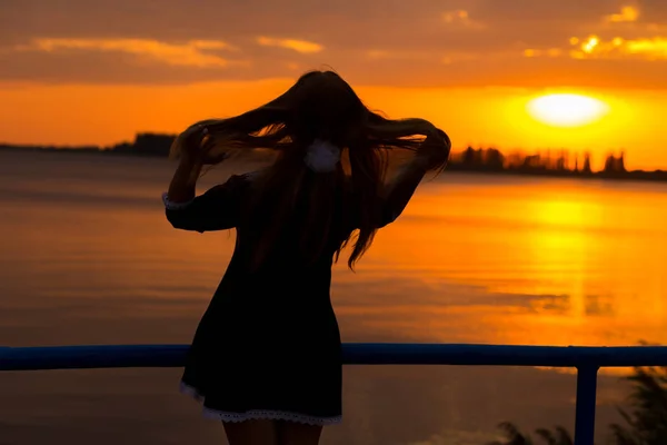 Vista laterale della luce posteriore di una silhouette donna che respira aria fresca e profonda all'alba calda di fronte al sole. leggerezza e ariosità femminile — Foto Stock