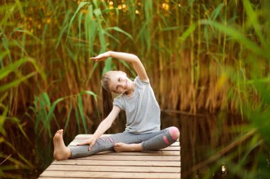 Çocuk platformu açık havada egzersiz yapıyor. Sağlıklı bir yaşam tarzı. Yoga-kız