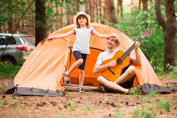 Padre e hija cerca de tienda de campaña tocando la guitarra en el bosque de verano — Foto de Stock