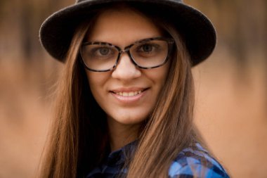 Sonbaharda şapka ve güneş gözlüğü ile genç kadının Moda açık hava portresi, retro tarzı renk tonları. Kadın modası.