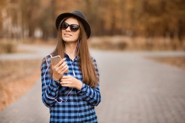 şık kadın güneş gözlüğü Sonbahar Park müzik dinlemek. Müzik keyfi
