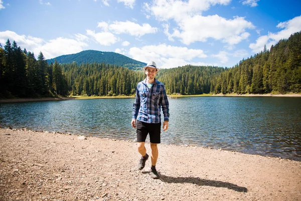 Man i hatt promenader utomhus Resor Livsstil semester koncept med sjö och berg på bakgrunden — Stockfoto