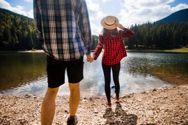 Tatil konsepti. Dağlarda iki yürüyüşçü göl ve yaz aylarında güneşli sıcak hava ile vadinin güzel görünümü zevk, yeşil ağaçlar etrafında, sevgi havada