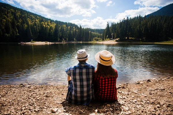 Pareja de viajeros admiran la vista del lago de montaña. Viajes y concepto de vida activa. Aventura y viajes en las montañas — Foto de Stock