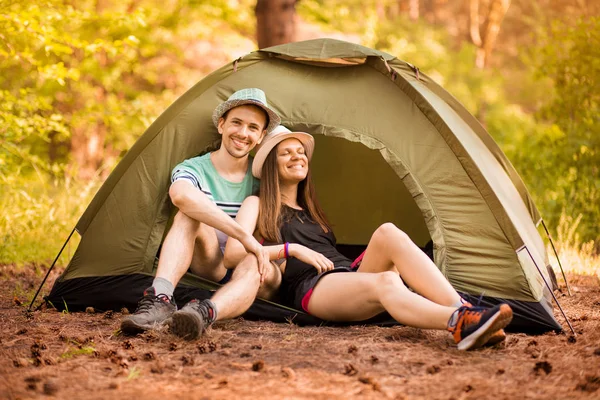 Romantic couple camping outdoors and sitting in tent. Happy Man and woman on romantic camping vacation.