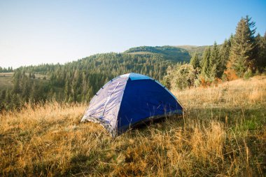 Sabah çadırı olan dağların manzarası. Sonbahar ormanında kamp dinlenmesi.