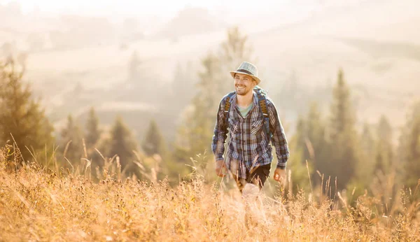 Barbudo turista en sombrero con mochila senderismo en el bosque de montañas. Caminante masculino caucásico al aire libre en la naturaleza . — Foto de Stock