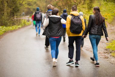 Bir grup arkadaşın sonbahar tatilinde sırt çantalarıyla birlikte yürüdüğü arka plan. Yürüyüş ve insanlar dostluk kavramı