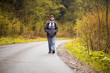 Yürüyüş. 60 yaşındaki son sınıf kadın yürüyüşçü gülerek sonbahar ormanında yürüyor. Etkin emeklilik kavramı