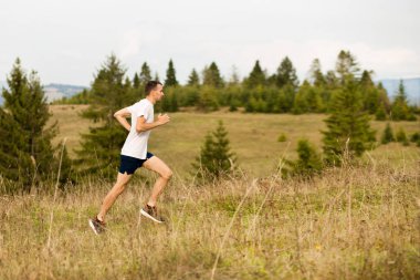 Koşu yapan fitness adamı arka planda güzel dağ manzarası olan açık havada koşuyor. Kafkas sporu erkek koşucu eğitimi maraton için.