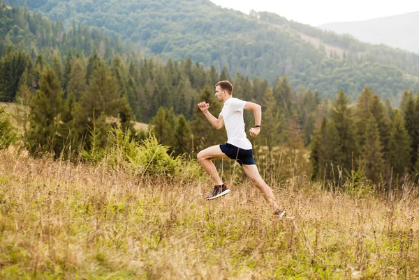 На задньому плані чоловік біжить надвір з гарними гірськими краєвидами. Кавказькі спортсмени готуються до марафону.. — стокове фото