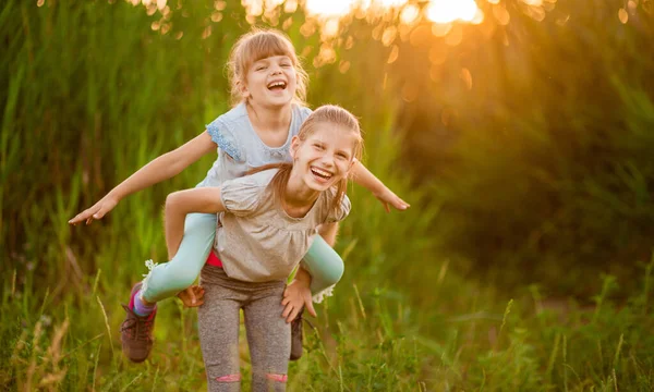 Dos Hermanitas Graciosas Jugando Afuera Atardecer Niña Subió Espalda Hermana —  Fotos de Stock