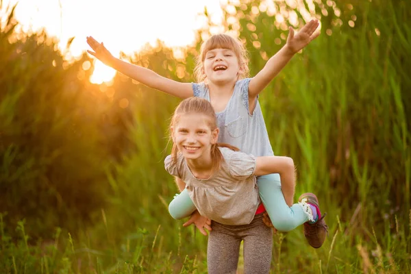 Dos Hermanitas Graciosas Jugando Afuera Atardecer Niña Subió Espalda Hermana —  Fotos de Stock