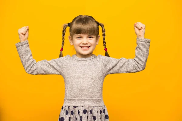 Позитивная Маленькая Девочка Смешными Косичками Показывает Свою Силу Бицепсы Поднятыми — стоковое фото