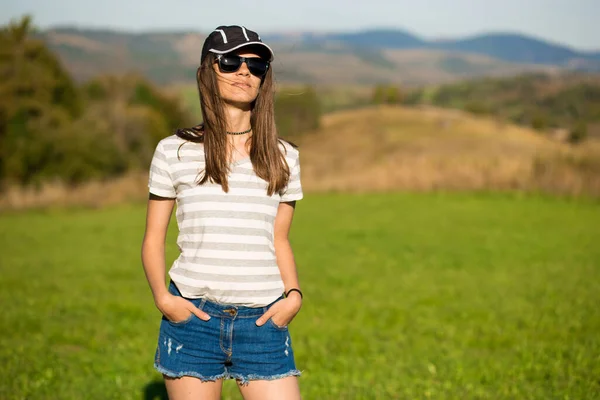Onbezorgde Vrolijke Vrouw Zonnebril Pet Jeans Shorts Wandelen Groene Grasweide — Stockfoto