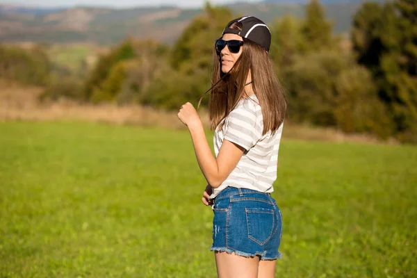 Onbezorgde Vrolijke Vrouw Zonnebril Pet Jeans Shorts Wandelen Groene Grasweide — Stockfoto