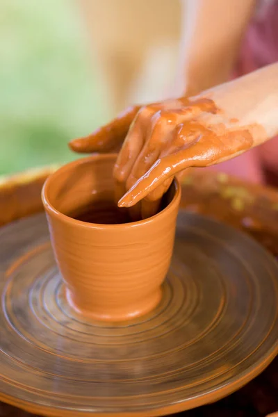 Woman hands sculpts cup from clay pot. Workshop of modeling on potter wheel.