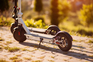 Sonbaharda gün batımında şehir şehrini keşfetmeye hazır iki modern elektrikli scooter. Ekolojik şehir taşımacılığı kavramı