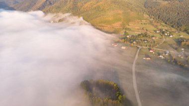 Sonbahar gündoğumunun bulutların üzerindeki dağ köyündeki hava aracı görüntüsü