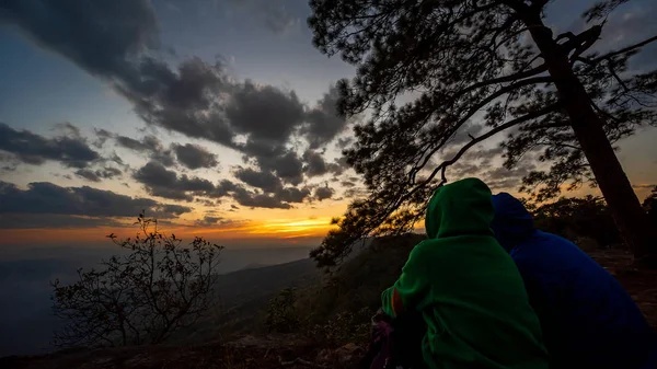 Men and women watching the sunset at Phu Kradueng National Park in Thailand.