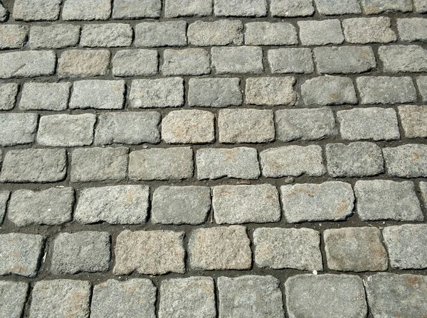 Gray stone road. Stone surface of the blocks. Background of the road.