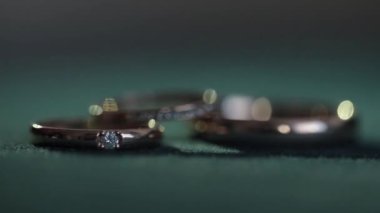 Koyu yeşil arka planda nikah yüzükleri.