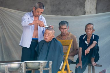 Guilin, Çin 18 Eylül 2017: erkek saç kesimi yol kenarına yerleştirilen bir Kuaför Guilin bir yerel sabah marketten alır 