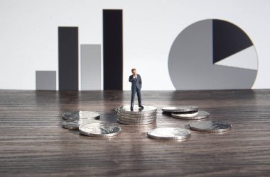 İş konsepti. Gümüş para yığınının üzerinde duran bir işadamı..