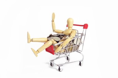 Alışveriş sepeti içinde gümüş sikke ile ahşap manken. İş kavramı.