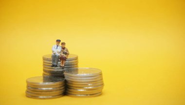 İş kavramı. Gümüş sikke yığını üzerinde oturan yaşlı çift.