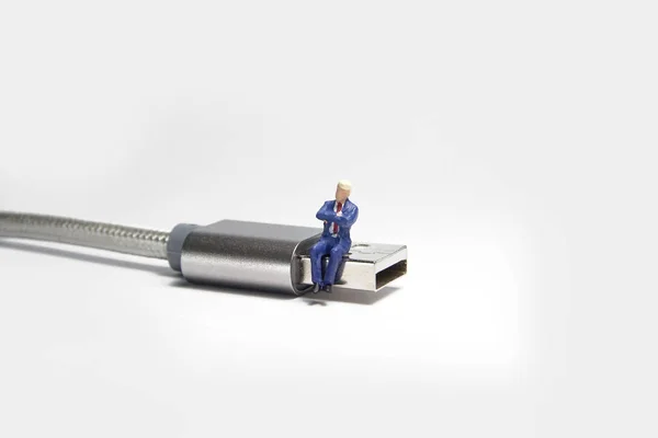 Zakenman figuur zittend op usb USB-kabel. E-commerce concept. — Stockfoto