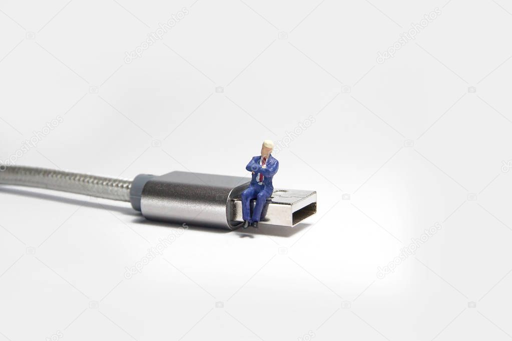 Businessman figure sitting on usb USB cable. E commerce concept.