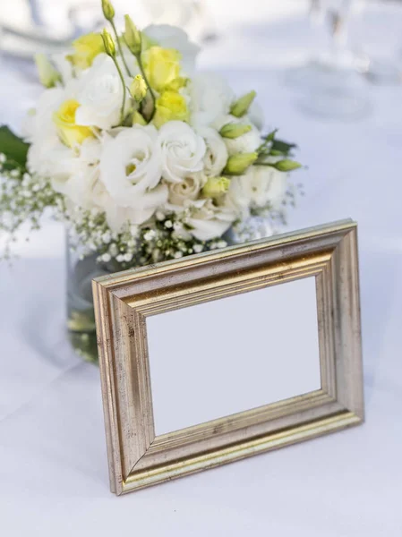 Bridal bouquet standing in a glass near an old, golden photo frame. Copy space. — Stock Photo, Image