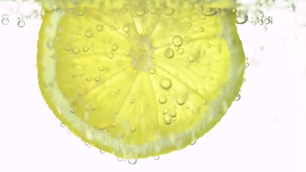 Концепция свежести, ломтик лимона в чистой воде, с освежающими пузырьками газа, крупным планом. Цитрусовые напитки. — стоковое видео