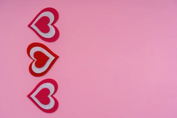 Verticale rode harten op een roze achtergrond. Conceptuele foto. Kopieerruimte. — Stockfoto