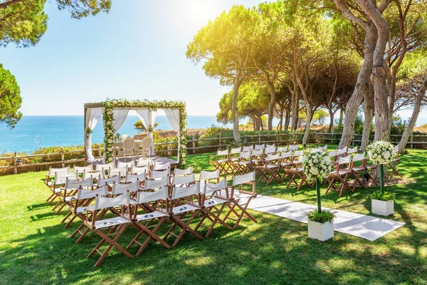 Hermosa boda junto al océano en un día soleado. Arco limpiado con flores . — Foto de Stock