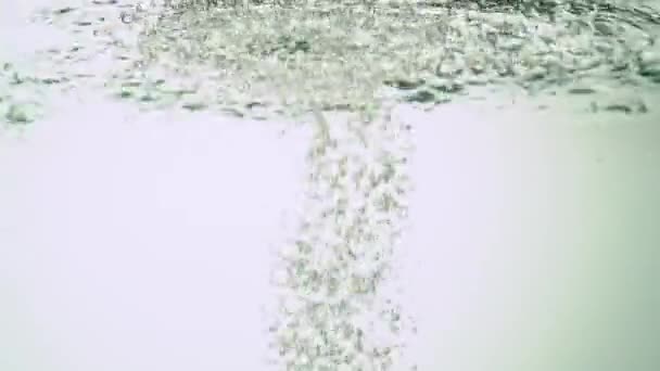 Ecologische rode peper wordt ondergedompeld in water, waardoor bubbels en waterschommelingen ontstaan. Op witte achtergrond. Close-up. — Stockvideo