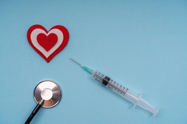 Mavi arka planda şırıngası olan bir doktor steteskobu için tıbbi ekipman, yakın plan. Boşluğu kopyala.