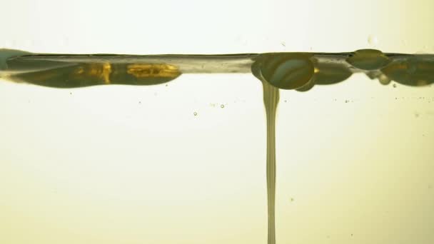 研究室のガラス容器の中で燃料、黄色の黄金の油が泡立つ。スペースのコピー. — ストック動画