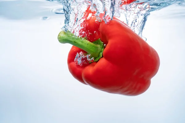 Red bell peppers on the surface of ecological clear water. Close-up. — Stock Photo, Image